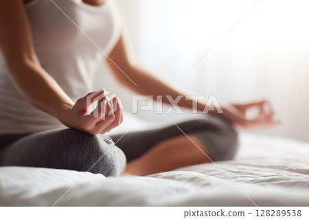 Close up of a woman hands in a lotus pose meditating on a bed at home 128289538