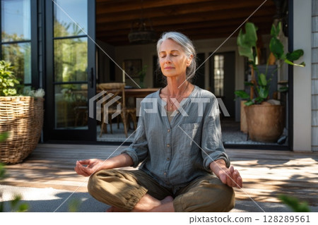 Photo of a senior woman in a yoga pose on a patio, meditating outdoors Photo of a senior woman in a yoga pose on a patio, meditating outdoors 128289561