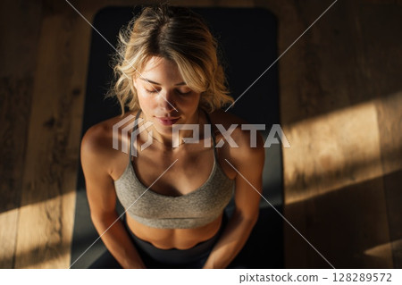 Young woman doing yoga stretches in the living room at home Young woman doing yoga stretches in the living room at home 128289572