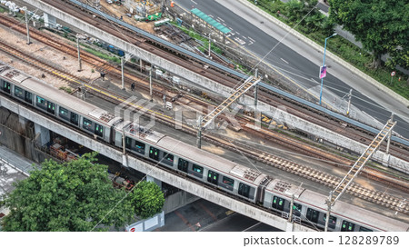 July 6 2025 Busy Railway Tracks with Modern Commuter Train and Surrounding Roadway 128289789