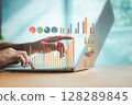 Hands pointing at colorful data charts on laptop screen, symbolizing business intelligence, digital analytics, and modern data visualization in the workplace. 128289845