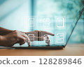 Typing on laptop with floating digital document icons, representing paperless workflow, cloud storage, and secure online document management in modern businesses. 128289846