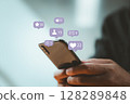 Close-up of hand holding smartphone with social media icons, symbolizing digital engagement, business communication, and modern mobile interaction platforms. 128289848