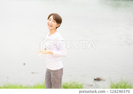Woman holding a plastic bottle in the park 128290370