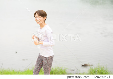 Woman holding a plastic bottle in the park 128290371