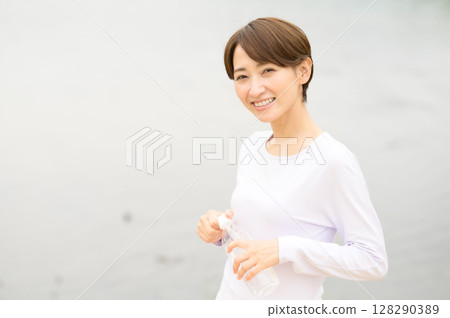 Woman holding a plastic bottle in the park 128290389