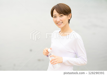 Woman holding a plastic bottle in the park Woman holding a plastic bottle in the park 128290391