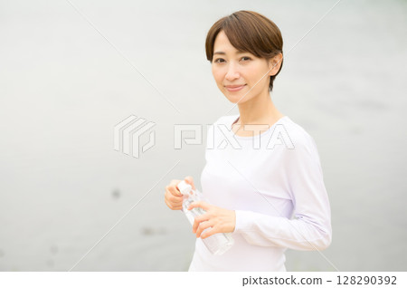 Woman holding a plastic bottle in the park 128290392