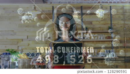 Small business owner holding open sign, smiling confidently amid pandemic challenges Small business owner holding open sign, smiling confidently amid pandemic challenges 128290591