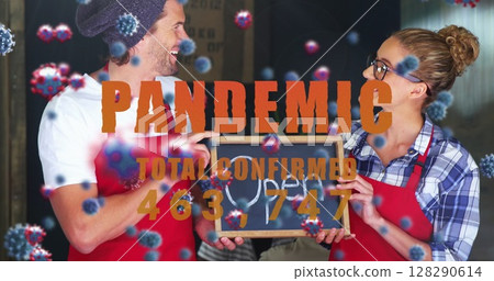 Cafe workers in red aprons holding open sign, smiling during pandemic 128290614