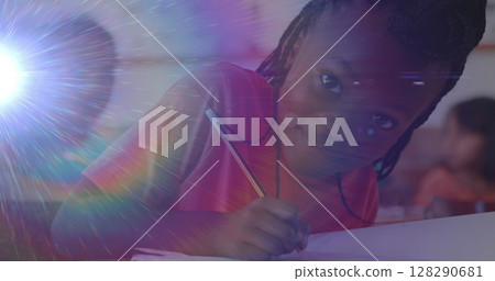 Image of portrait of happy biracial schoolgirl writing during lesson at school smiling to camera Image of portrait of happy biracial schoolgirl writing during lesson at school smiling to camera 128290681