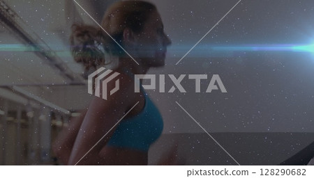 Image of caucasian woman running on treadmill in gym with glowing blue light Image of caucasian woman running on treadmill in gym with glowing blue light 128290682