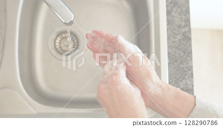 Washing hands with soap at kitchen sink for hygiene and safety Washing hands with soap at kitchen sink for hygiene and safety 128290786