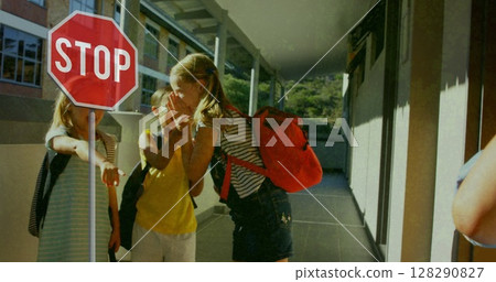 School children with backpacks laughing and playing near stop sign outdoors 128290827