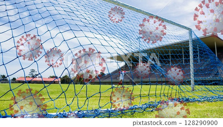 Image of 3d coronavirus cells floating over soccer player kicking ball on empty stadium 128290900