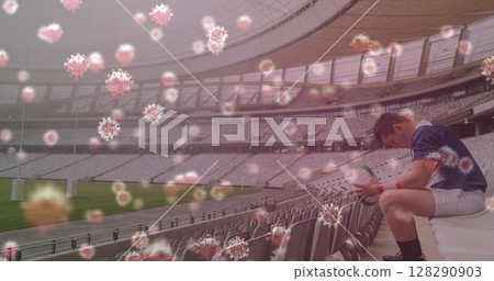 Image of 3d coronavirus cells floating over rugby player holding rugby ball on empty stadium 128290903