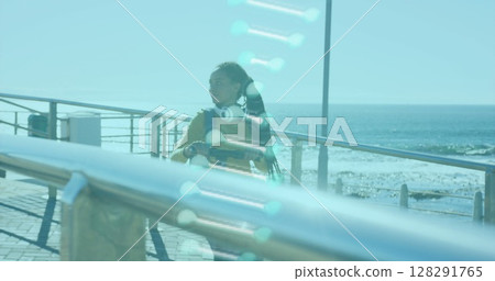 Image of dna strand spinning over woman walking with electric scooter by seaside 128291765