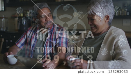 Image of biohazard symbol, covid 19 cells and text over senior couple using tablet at home Image of biohazard symbol, covid 19 cells and text over senior couple using tablet at home 128293083