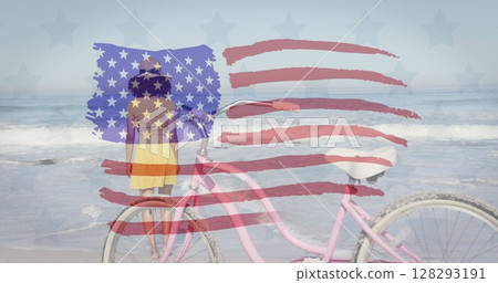 American flag waving against rear view of african america woman with bicycle standing at the beach 128293191