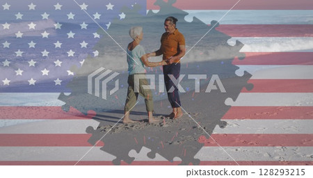 Image of american flag jigsaw puzzle revealing confetti and senior couple dancing on beach 128293215