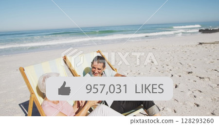 Image of speech bubble with thumbs up icon and numbers over couple in deckchairs on beach 128293260