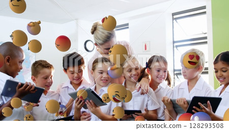 In school, diverse students and teacher using tablets with floating emojis 128293508