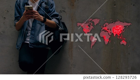 Young man checking smartphone with world map highlighting pandemic hotspots 128293726