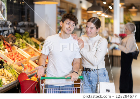 Couple man and woman with shopping cart choosing products 128294677