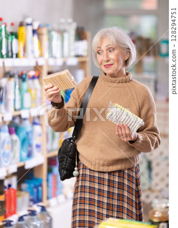 Positive mature woman choosing clothes pegs in department store 128294751