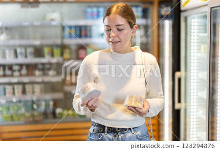 Young woman choosing cheese in grocery supermarket Young woman choosing cheese in grocery supermarket 128294876