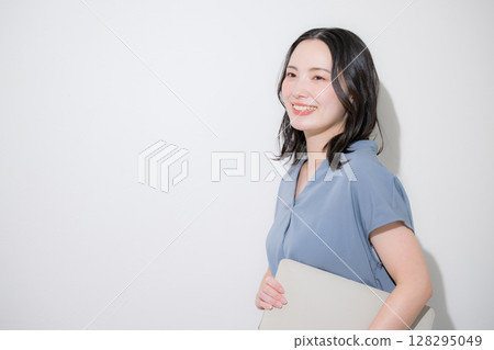A refreshing spring/summer short-sleeved business (office casual) woman holding a computer on a white background A refreshing spring/summer short-sleeved business (office casual) woman holding a computer on a white background 128295049