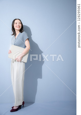 在淺藍色背景中，一位身著清爽春夏短袖商務（辦公休閒）服裝的女性手持筆記型電腦 招聘 128295061