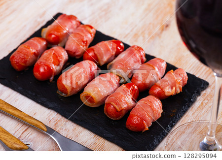 Sausage rolled with bacon on black dish 128295094