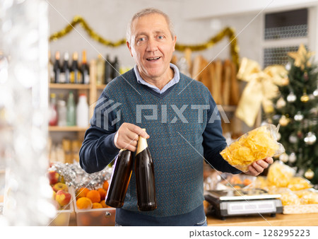 Mature man buys bottles of beer and crisps to celebrate Christmas 128295223
