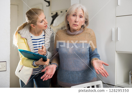 Surprised elderly woman cannot answer questions of interviewer at home Surprised elderly woman cannot answer questions of interviewer at home 128295350