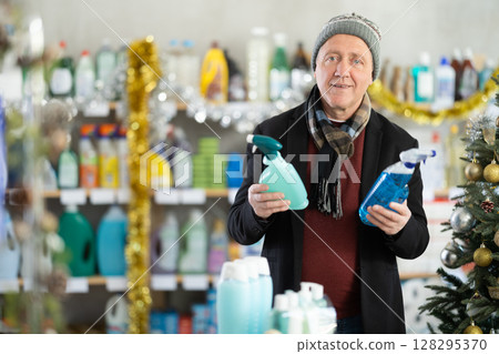 In Christmas atmosphere, senior man studies label and choose kitchen cleaner spray In Christmas atmosphere, senior man studies label and choose kitchen cleaner spray 128295370