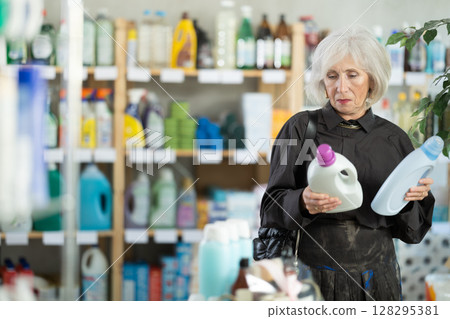 Elderly woman consumer with household chemical products for washing indoors Elderly woman consumer with household chemical products for washing indoors 128295381