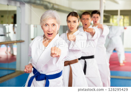 Group lesson in karate or taekwondo in gym. Practicing blows 128295429