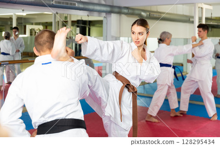 Woman and man in kimono and belts fighting during karate training 128295434