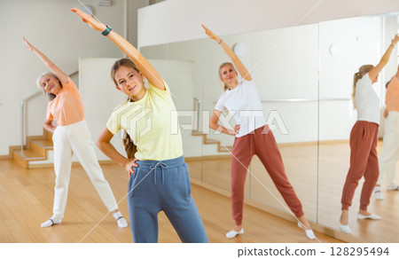Teenage girl doing bending sideways with her family during fitness training Teenage girl doing bending sideways with her family during fitness training 128295494