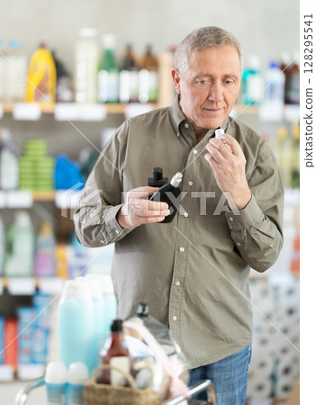 Elderly man choosing perfume in a European supermarket Elderly man choosing perfume in a European supermarket 128295541