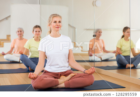 Continuity of generations - family in lotus position doing yoga in gym Continuity of generations - family in lotus position doing yoga in gym 128295559