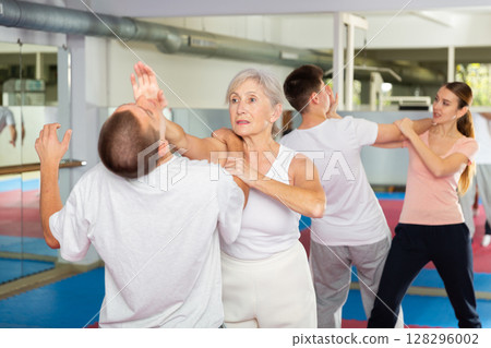 Elderly woman is training with man on self-defense course in gym 128296002