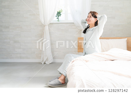 一名女子醒來後在床上伸懶腰 一名女子醒來後在床上伸懶腰 128297142