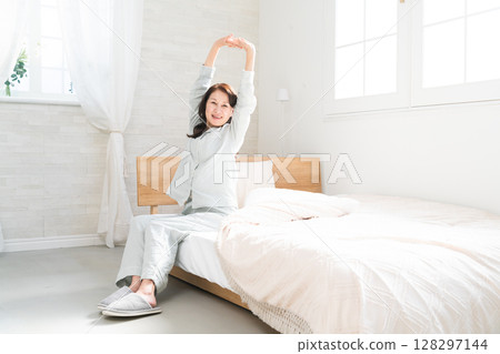 一名女子醒來後在床上伸懶腰 128297144