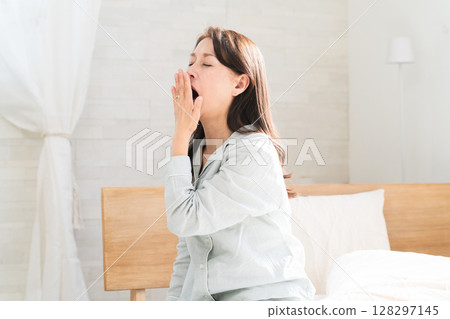 Woman yawning in bed after waking up 128297145