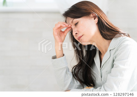 A woman wakes up in bed and complains of a headache A woman wakes up in bed and complains of a headache 128297146