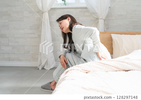 一名女子在床上醒來並抱怨背痛 一名女子在床上醒來並抱怨背痛 128297148