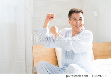An energetic man waking up and pumping his fist in bed 128297160