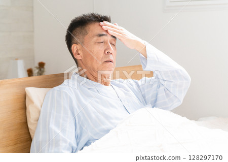 Man holding his head on bed 128297170
